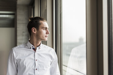 Junger Geschäftsmann schaut aus dem Fenster - UUF10051