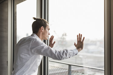 Junger Geschäftsmann schaut aus dem Fenster - UUF10052