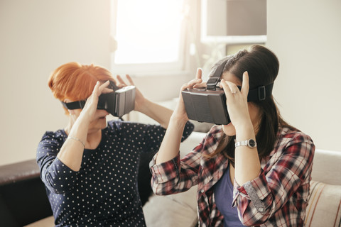 Adult daughter with mother at home wearing VR glasses stock photo