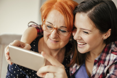 Glückliche erwachsene Tochter mit Mutter, die ein Selfie macht, lizenzfreies Stockfoto