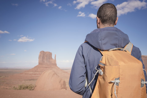 USA, Utah, Rückenansicht eines Mannes mit Rucksack mit Blick auf das Monument Valley, lizenzfreies Stockfoto