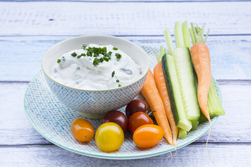 Schale mit Kräuter-Joghurt-Dip, Kirschtomaten und Gemüsesticks auf dem Teller - LVF05923