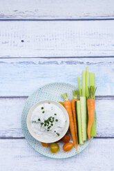 Schale mit Kräuter-Joghurt-Dip, Kirschtomaten und Gemüsesticks auf dem Teller - LVF05924