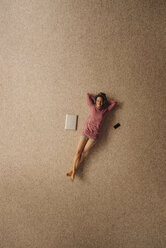 Woman lying on carpet wearing headphones, top view - JOSF00632