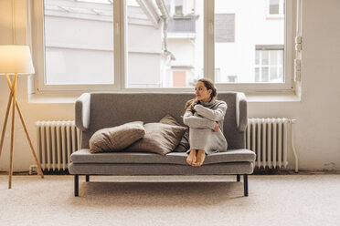 Woman sitting on couch looking sideways - JOSF00635