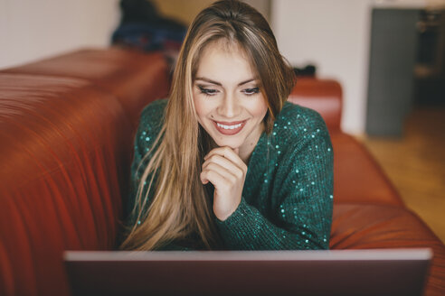 Young woman relaxing on the couch using laptop - LCUF00106