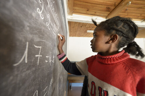 Madagaskar, Girl in Fianarantsoa elementary school calculatiing at blackboard - FLKF00757