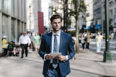 Gutaussehender Geschäftsmann, der in Manhattan spazieren geht und ein digitales Tablet trägt - GIOF02049