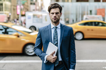 Handsome businessman walking in Manhattan, carrying digital tablet - GIOF02056