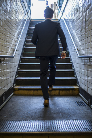 Hektischer Geschäftsmann läuft auf die Treppe einer U-Bahn-Station zu, lizenzfreies Stockfoto