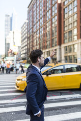 Businessman in the streets of Manhattan hailing a cab - GIOF02070