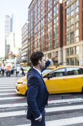 Geschäftsmann in den Straßen Manhattans, der ein Taxi ruft - GIOF02070