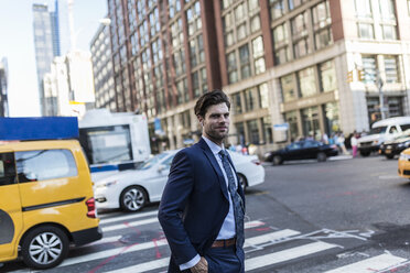 Geschäftsmann in den Straßen von Manhattan mit gelbem Taxi im Hintergrund - GIOF02071