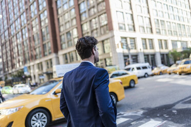 Geschäftsmann in den Straßen von Manhattan mit gelbem Taxi im Hintergrund - GIOF02072