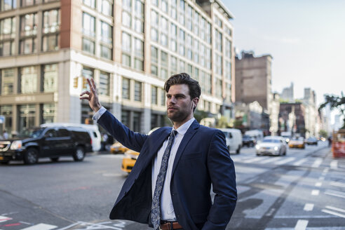 Geschäftsmann in den Straßen Manhattans, der ein Taxi ruft - GIOF02073