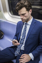 Businessman in metro using smart phone - GIOF02076