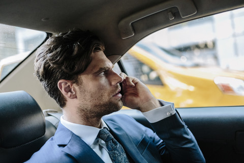 Geschäftsmann sitzt im Taxi und benutzt ein Smartphone, lizenzfreies Stockfoto