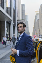 Businessman exiting yellow taxi in Manhattan - GIOF02087