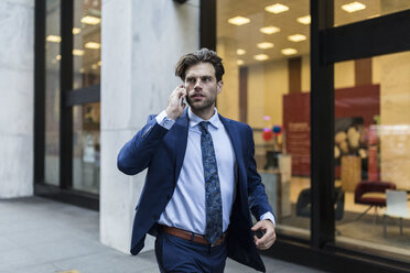 Alleinstehender Geschäftsmann in Eile, der durch Manhattan läuft und sein Smartphone benutzt - GIOF02094