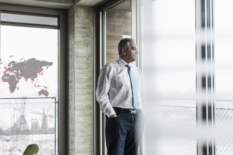 Geschäftsmann schaut im Büro aus dem Fenster, lizenzfreies Stockfoto