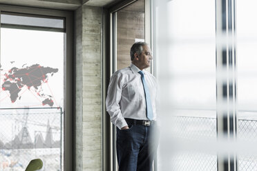 Geschäftsmann schaut im Büro aus dem Fenster - UUF10069