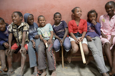 Madagaskar, Fianarantsoa, Schulkinder sitzen auf einer Bank in einer Reihe - FLKF00765