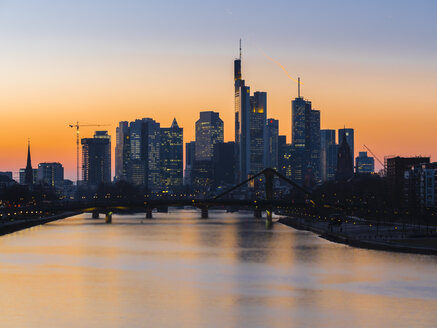 Deutschland, Frankfurt, Blick auf Skyline mit Flößerbrücke und Main im Vordergrund in der Dämmerung - AMF05300