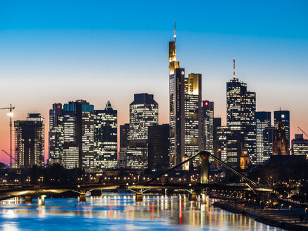 Deutschland, Frankfurt, Blick auf Skyline mit Flößerbrücke und Main im Vordergrund in der Dämmerung - AMF05302