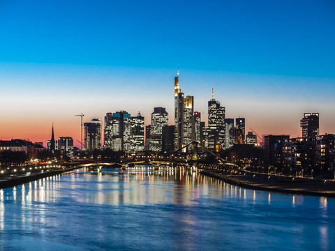 Deutschland, Frankfurt, Blick auf Skyline mit Flößerbrücke und Main im Vordergrund in der Dämmerung, lizenzfreies Stockfoto