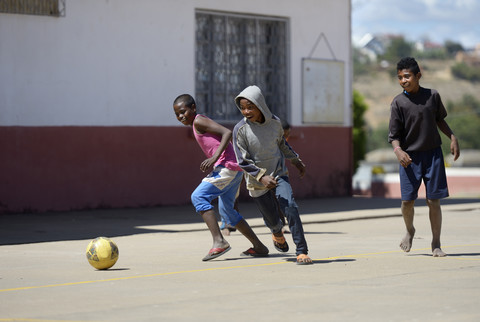 Madagaskar, Fianarantsoa, Junge spielt Fußball auf dem Schulhof, lizenzfreies Stockfoto