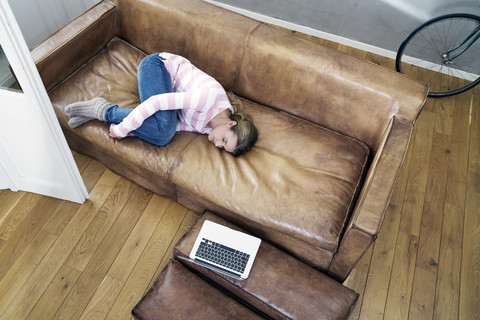 Frau entspannt auf Ledercouch zu Hause, lizenzfreies Stockfoto