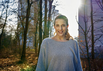 Portrait of smiling blond woman at backlight - FMKF03574