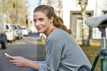 Portrait of smiling blond woman with cel phone - FMKF03576