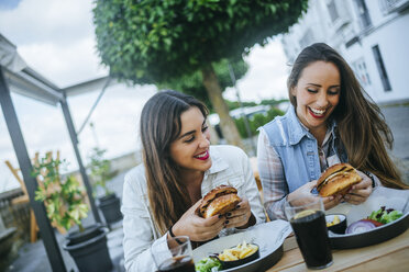 Zwei Frauen essen Hamburger in einem Straßenrestaurant - KIJF01300