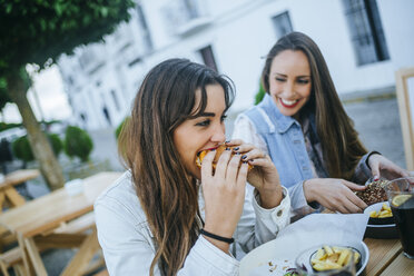 Two women eating Hamburgers in a street restaurant - KIJF01303