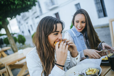 Zwei Frauen essen Hamburger in einem Straßenrestaurant - KIJF01303