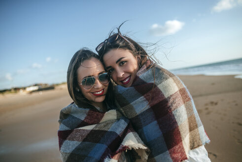 Porträt von zwei mit einer Decke bedeckten Frauen am Strand - KIJF01314