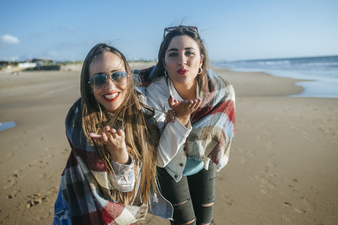 Porträt von zwei jungen Frauen am Strand, die sich küssen, lizenzfreies Stockfoto