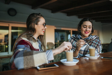 Zwei junge Frauen trinken Kaffee in einem Straßencafé - KIJF01336