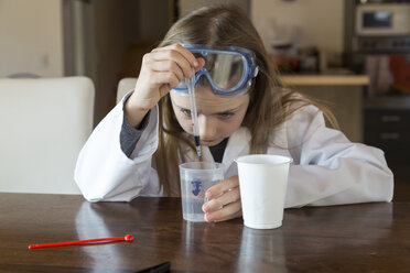 Girl wearing work coat and safety glasses using chemistry set at home - SARF03222