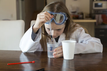 Mädchen mit Arbeitskittel und Schutzbrille bei der Arbeit mit einem Chemiebaukasten zu Hause - SARF03222