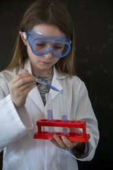 Porträt eines Mädchens mit Arbeitskittel und Schutzbrille bei einem chemischen Experiment - SARF03226