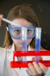 Porträt eines Mädchens mit Arbeitskittel und Schutzbrille bei einem chemischen Experiment - SARF03227
