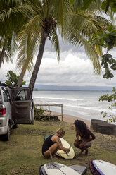 Indonesien, Java, zwei Frauen bereiten ein Surfbrett an der Küste vor - KNTF00650