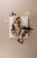 Frau liegt mit ihren Hunden im Bett und liest ein Buch - JOSF00652