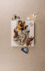 Frau liegt mit ihren Hunden im Bett und kuschelt - JOSF00653