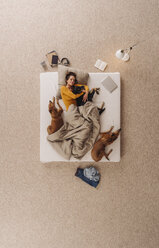 Woman lying in bed with her dogs, cuddling - JOSF00653