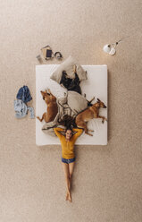 Frau liegt mit Hunden auf dem Boden ihres Bettes - JOSF00656