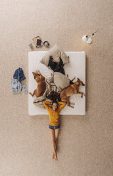 Woman lying at the bottom of her bed with dogs - JOSF00656