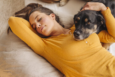 Frau im Bett liegend mit ihrem Hund - JOSF00659